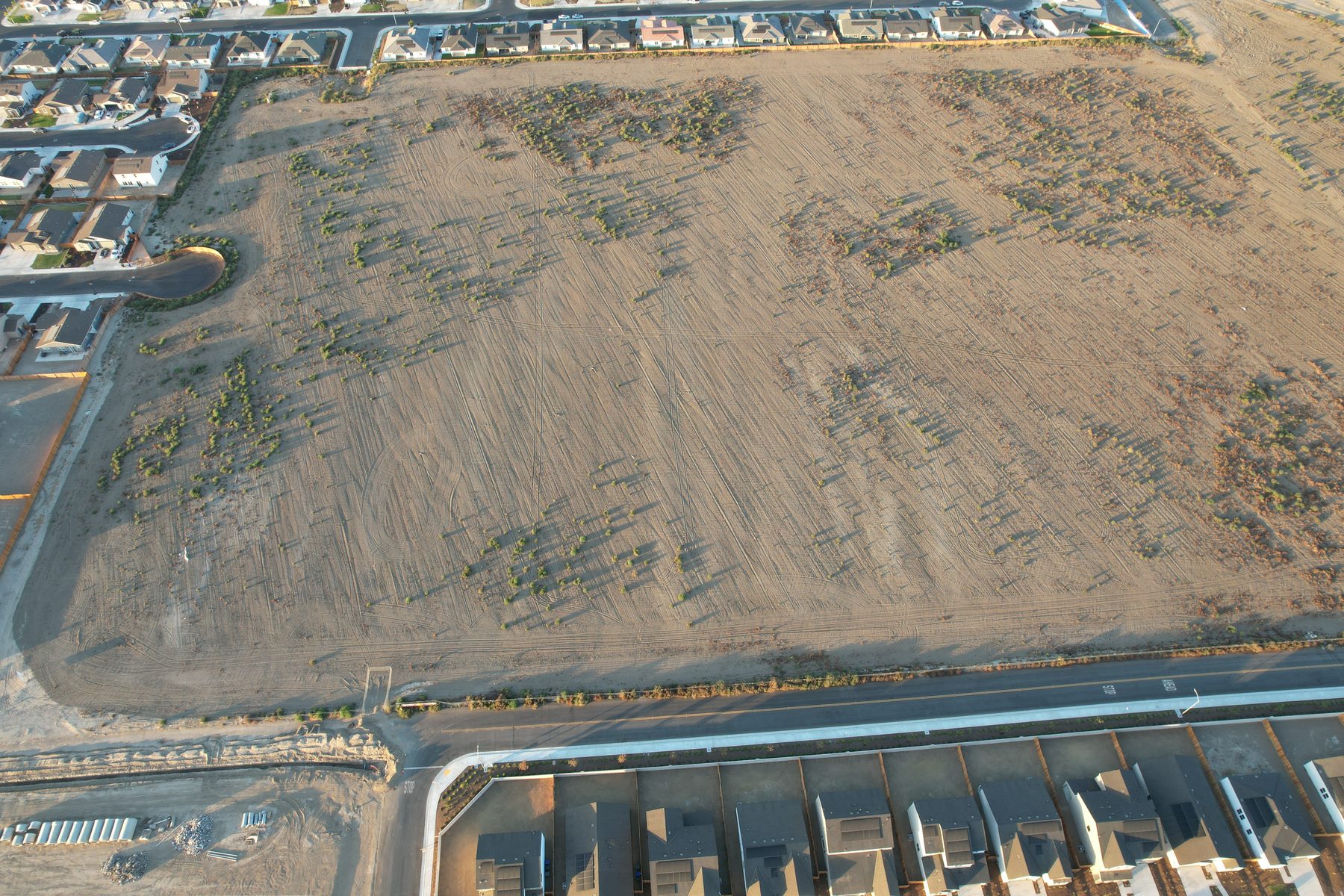 Aerial view of a graded parcel adjacent to newly built homes in Bakersfield